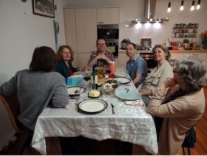 People at a dinner table, in a home, with a pretty table cloth full of Jewish symbols